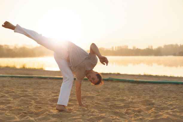 istock Athletic capoeira performer workout training on the beach sunris 993118862