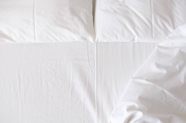 White bedding sheets and pillows White bedding sheet, blanket and pillows in the hotel room. Rest, sleeping, comfort concept. Top view. Copy space. bed sheets stock pictures, royalty-free photos & images