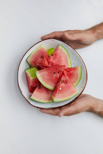 istock partial view of man holding bowl with watermelon pieces in hands on white surface 993143476