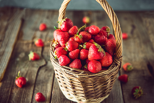 Ripe sweet strawberries in wicker basket on lold wooden rustic table. Agriculture farmer harvest. concept. Eco, organic vegitarian summer diet food. Vintage toning. Selective focus. Copy space.