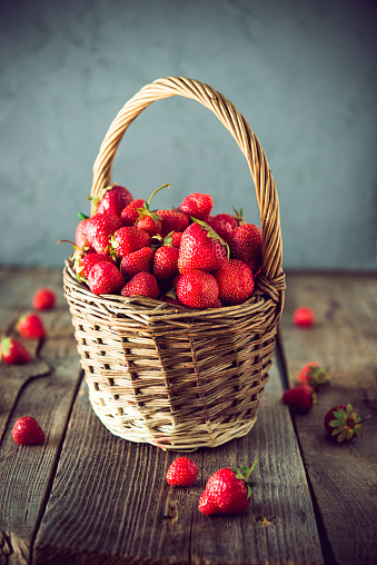 Ripe sweet strawberries in wicker basket on lold wooden rustic table. Agriculture farmer harvest. concept. Eco, organic vegitarian summer diet food. Vintage toning. Selective focus. Copy space