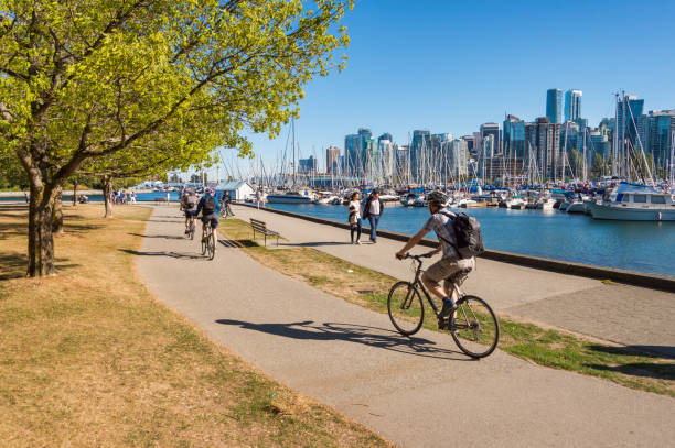 Stanley Park and Vancouver Skyline. Vancouver, British Columbia, Canada - 14 September 2017: People riding bikes in Stanley Park. vancouver canada stock pictures, royalty-free photos & images