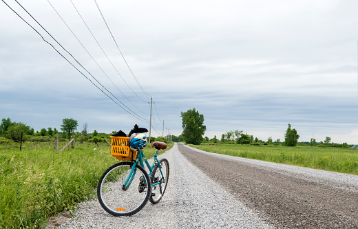 Bike with a basket parked on the side of a gravel road