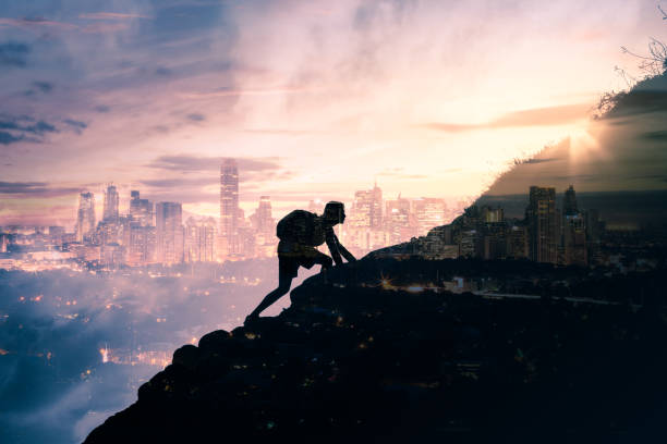 istock Man climbing up mountain against city background. 993186202