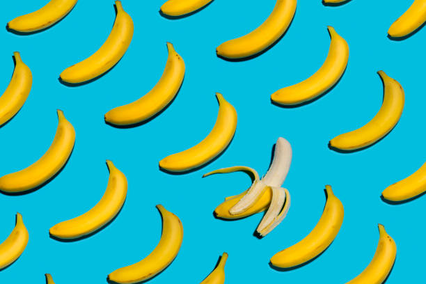 plátanos amarillos sobre fondo azul simétrico con una pelan abierto - plátano fruta tropical fotos fotografías e imágenes de stock