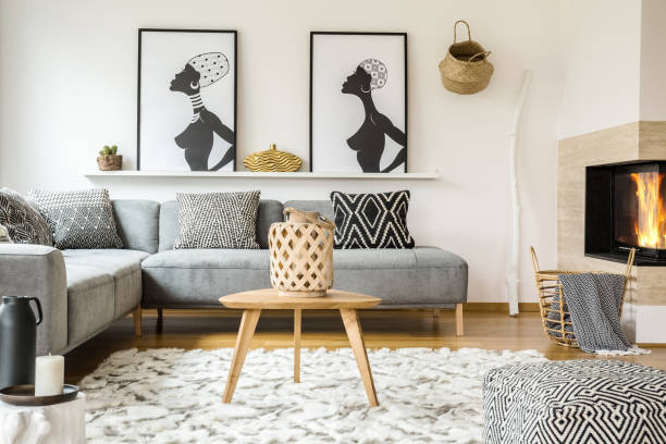 istock Wooden table on carpet in african living room interior with patterned cushions on grey sofa. Real photo 993243228
