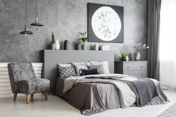 コンクリートの壁にポスターと灰色の寝室のインテリアでベッドの横に椅子。実際の写真 - pillow headboard wall bedroom ストックフォトと画像