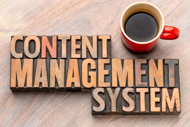 content management system - word abstract in vintage letterpress wood type blocks with a cup of coffee