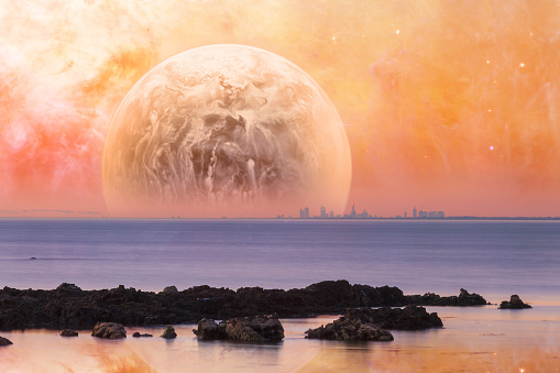 Fantasy landscape - modern city skyline across sea with rock formations on the foreground and huge alien planet in orange sky. Elements of this image are furnished by NASA