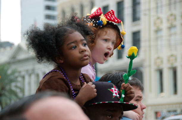 New Orleans, Louisiana, USA - 2018: Two girl watch a parade during the Mardi Gras celebrations.