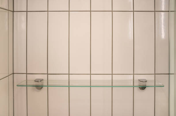 Empty glass shelf on shower wall with rectangle white tiles