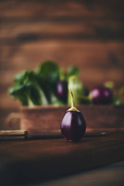 aubergine bébé sur planche à découper avec couteau - italian eggplant photos et images de collection