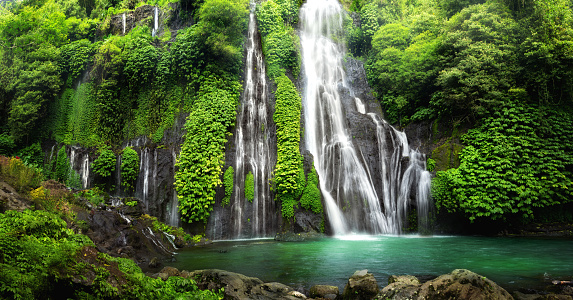 Hidden jungle waterfall cascade in tropical rainforest with rock and turquoise blue pond. Its name Banyumala because its twin waterfall in mountain slope