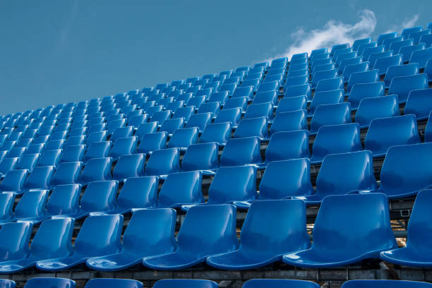 leere blaue sitz im fußballstadion mit blauem himmel - bleachers stadium empty seat stock-fotos und bilder