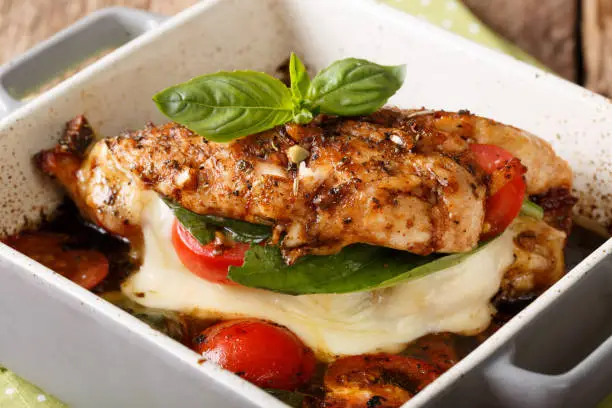 Delicious chicken fillet baked with caprese close-up in a baking dish on a table. horizontal