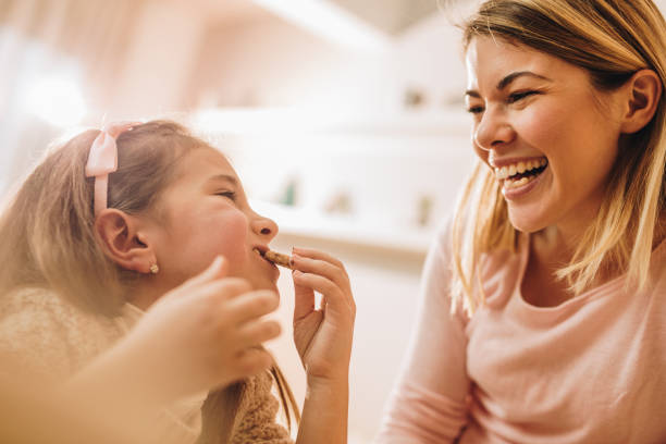 garota feliz, fazendo com que a mãe dela rir enquanto come um bolinho em casa. - cookie chocolate chocolate chip chocolate chip cookie - fotografias e filmes do acervo