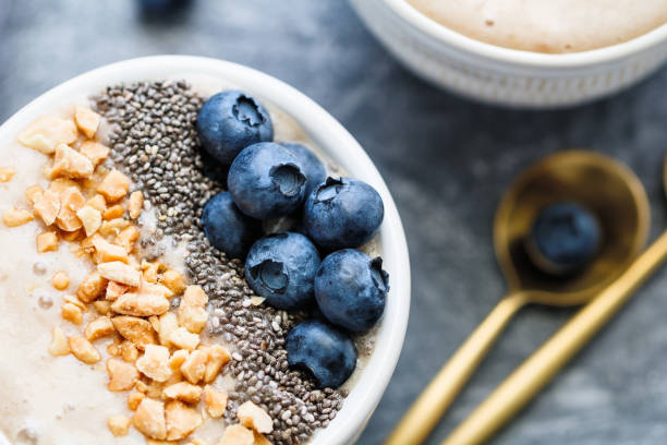 istock Banana dessert with chia seeds, fresh blueberry and nuts over grey table. 993397166