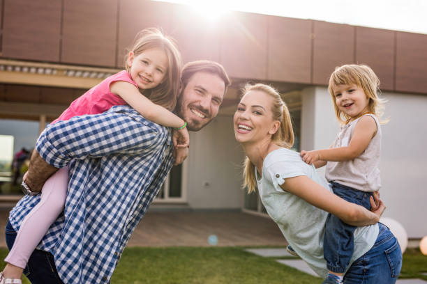 istock Young playful family having fun while piggybacking in the front yard. 993400900