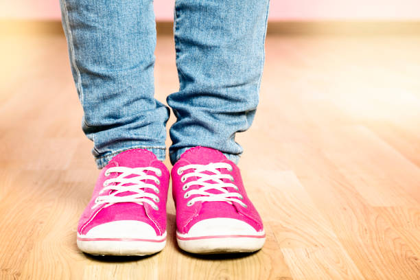istock Cropped denim jeans legs over bright pink sneakers 993404998