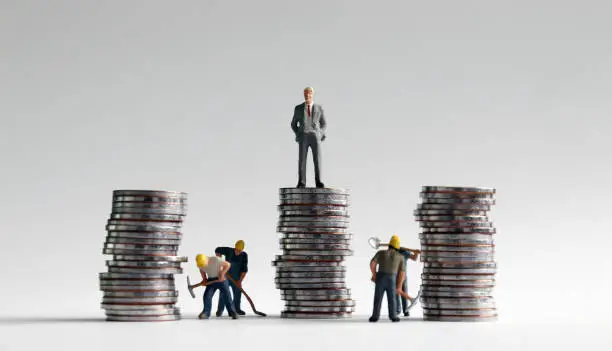 Photo of Miniature people and three pile of coins.