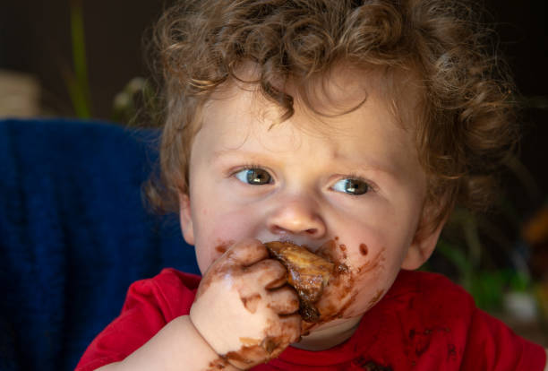 istock a baby is eating a chocolate cake 993419376