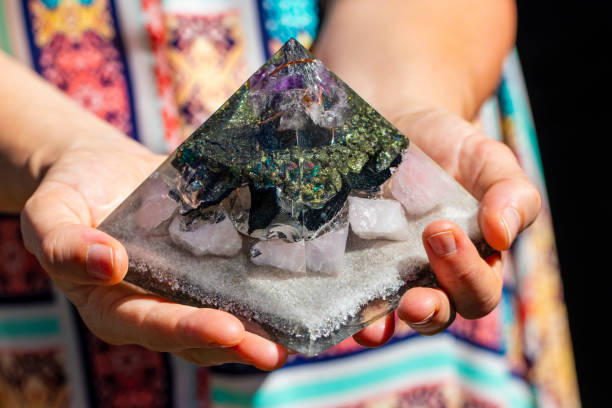 uma mão segurando um bela pirâmide orgonite gerador - amethyst necklace gem purple - fotografias e filmes do acervo
