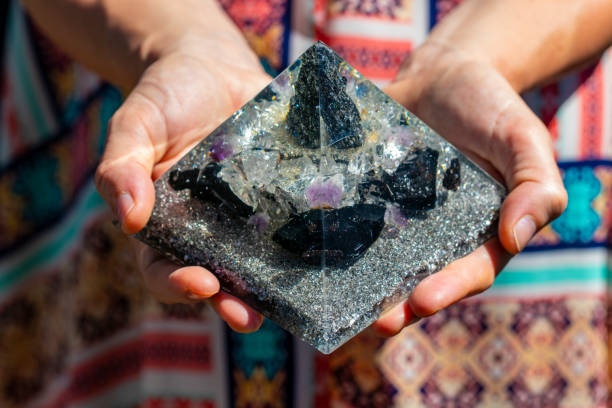 uma mão segurando um bela pirâmide orgonite gerador - amethyst necklace gem purple - fotografias e filmes do acervo