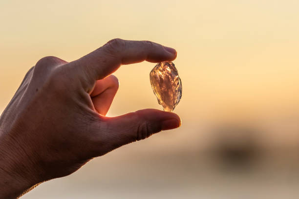 une main tenant un cristal améthyste belle à l’extérieur au soleil - transparent crystal crystal ball human hand photos et images de collection