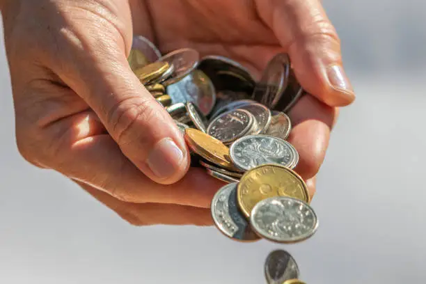 Photo of A Hand Holding and Dropping Coins