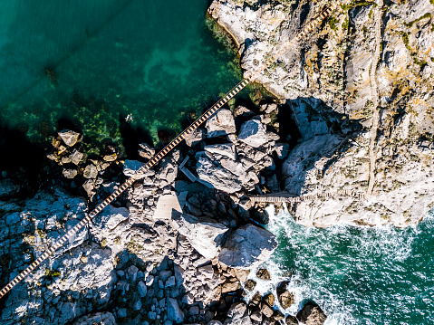 rope bridge between the rocks over the sea waves and stones