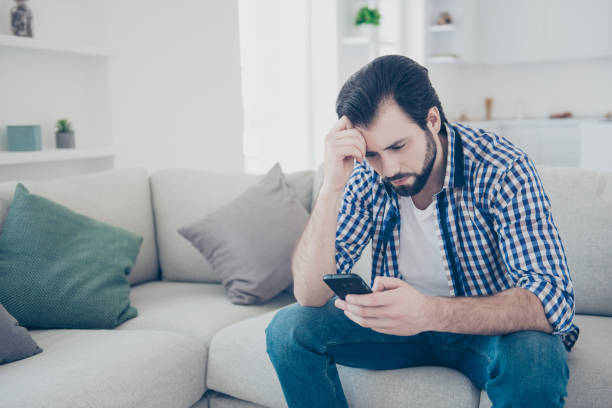 istock Portrait of tired alone serious man sitting indoor using smart phone, internet, checking email, having problem in relationship chatting with his girlfriend worry about bad news 993458200