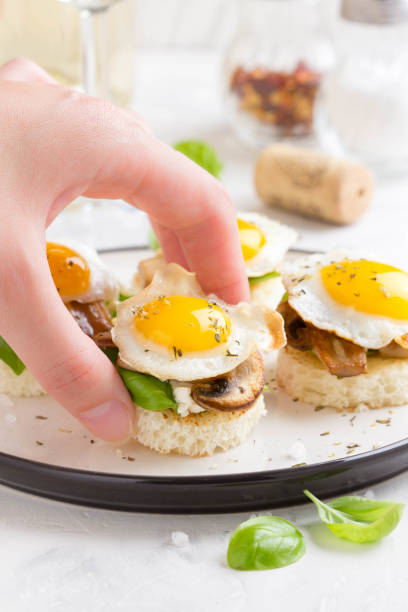 Canapes with fried mushrooms, quail egg, soft cheese and basil, beautiful appetizer for home party or event
