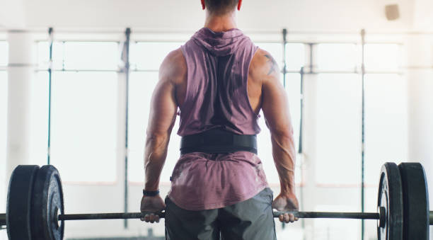 Hold onto the things that make you strong Rearview shot of a muscular man lifting a barbell in a gym belt stock pictures, royalty-free photos & images