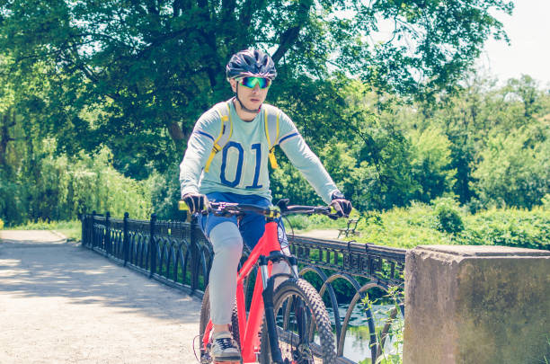 istock Cyclist in helmet riding in park on bridge 993466230