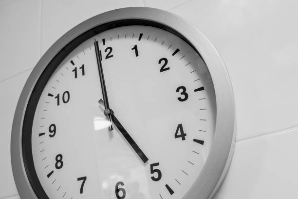 istock closeup simple clock on white wall time at 5 o'clock 993470172