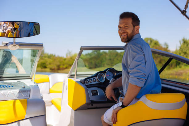 istock Charming young man posing behind steering wheel of yacht 993481054