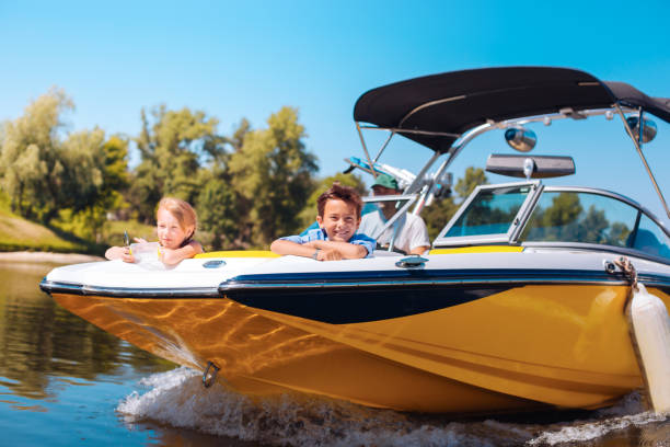 Cheerful little siblings enjoying view from boat bow Breathtaking view. Joyful little siblings sitting on the bow of the boat and contemplating the view while smiling happily sail stock pictures, royalty-free photos & images