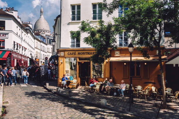Paris, France - August 10, 2017. Montmartre Paris street leading to Basilica of Sacred Heart of Paris with people, cafe Montmartre with summer terrace and old classical parisian buildings by summer.