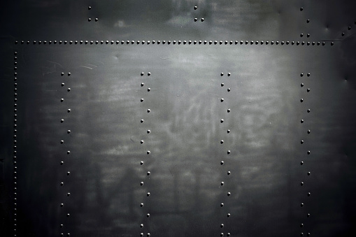 Iron cladding of the old locomotive of black color with rivets in vintage style. Industrial background.