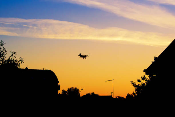 istock Biplane flying over roofs and trees in vibrant sunset 993578660