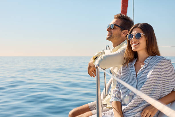 Life’s even better when you’re cruising Shot of a young couple enjoying a cruise out on the ocean sailing couple stock pictures, royalty-free photos & images