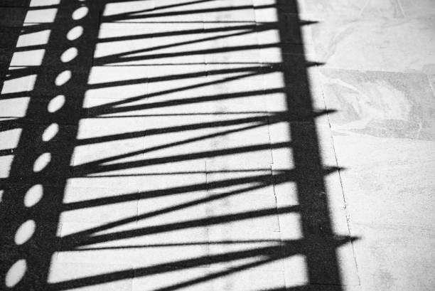 istock Abstract Shadows of Lines and Figures on a Road as Background or Texture, Black and White Picture 993598542