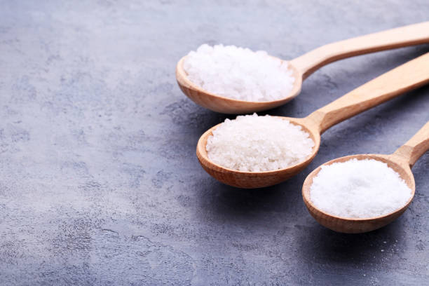 istock White sea salt in spoons on grey wooden table 993611678