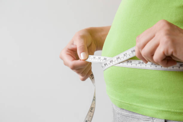 fat overweight woman measuring her waist. plus size. new start for healthy lifestyle, body slimming and weight loss. care about body. copy space. empty place for text on gray background. - dieting overweight weight scale healthcare and medicine imagens e fotografias de stock