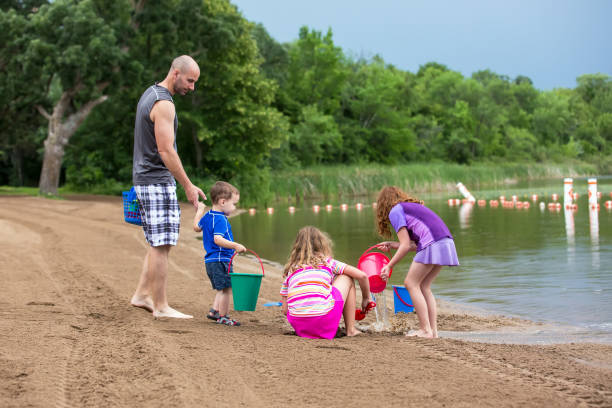 istock Father & Three Young Children Playing At the Beach 993616850