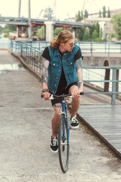 istock handsome stylish tattooed man riding bicycle on bridge 993617028