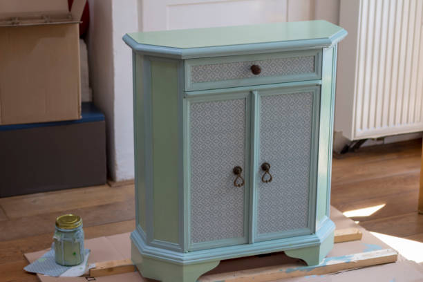 DIY old furniture DIY series or makeover series of old furniture. Cupboard or cabinet make-over from old-style oak wood or timber into French style with blue and green paint and some glued pieces of a plastic tablecloth on the small door panels and on the drawer. Before painting prepared with sandpaper and cleaning al the sawdust. door panel stock pictures, royalty-free photos & images