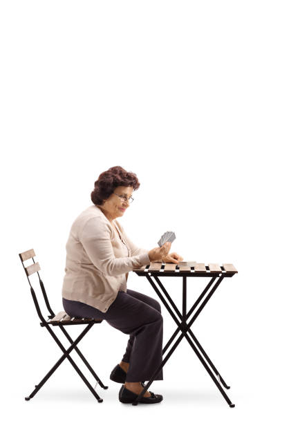 istock Senior lady sitting at a table and playing cards 993625522