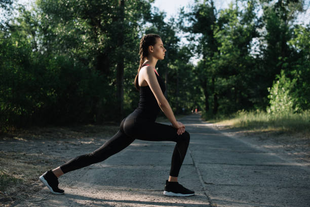 istock athletic woman stretching or doing lunges on road in park 993630206