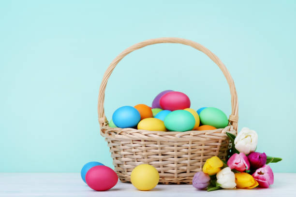 istock Colorful easter eggs in basket with tulips on wooden table 993631266